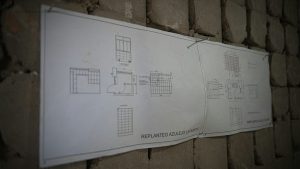Planos de replanteo de una reforma integral de piso colgados en la pared de obra en Zaragoza